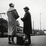 168252 Afbeelding van twee treinreizigers op het perron van het N.S.-station Amsterdam C.S. te Amsterdam, met op de ...